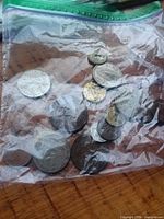 Bag filled with assorted world coins on wooden surface