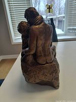 Rear view of bronze-tone plaster sculpture showing embracing couple and overall form