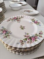Stack of twelve Moss Rose plates showing pattern and gold rim