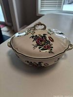 Top view of lidded serving bowl showing floral pattern and loop finial