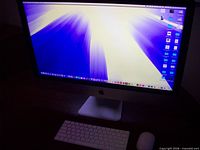 iMac powered on with keyboard and mouse on desk