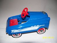 Left side view of blue pedal car showing side graphics, red seat, steering wheel, wheels