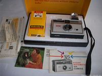 Camera outfit in box showing camera, film, manuals, flashcube