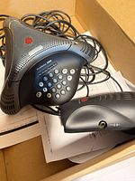 Conference phone, keypad visible, cords attached