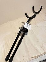 Overall view of black saxophone stand with padded cradle and foldable legs