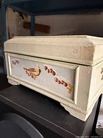 Front view showing bird and berries motif, light green paint, bracket feet