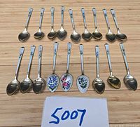 Front view showing 18 spoons with enamel handles and gold-washed bowls