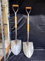 Two polished ceremonial shovels side by side