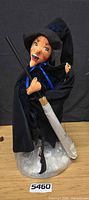 Full view of Annalee witch doll with broom, base wrap visible