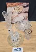 Group view showing all items including boxed charger plates, crystal vase, bowls, ice bucket
