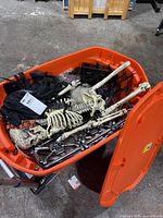 Open orange tote showing skeleton, fabric, and assorted decorations