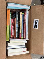 Open box showing stacked books with visible titles Jamaica, Sweet Taste of History, etc.