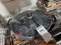 Overall view of Curtis Stone electric skillet with lid on rack