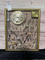 Front view of framed acrylic artwork showing embedded watch parts and gold-tone frame