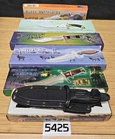 Stack of six boxed knives with model names visible