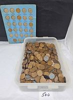 Loose wheat pennies in plastic tub with Whitman folder behind