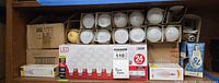 Shelf containing multiple boxed and loose light bulbs of varying wattages and types