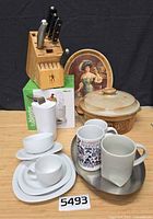 Group shot of all kitchen items including knife block, dinnerware, mugs, trays, casserole, Isablender box