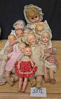 Group shot of all nine vintage dolls on wooden surface
