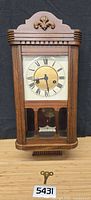 Full view of wooden pendulum wall clock with key