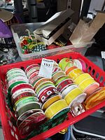 Basket containing numerous ribbon spools; clear tub with Christmas ornaments visible behind