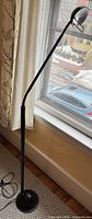 Full view of black metal halogen floor lamp standing by window