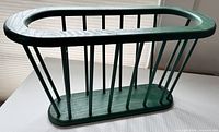 Overall view of green wooden magazine rack, oval opening, spindle sides