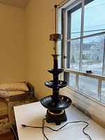 Full lamp standing on table, side view showing tiered ceramic bowls and brass base