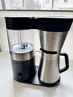 Front view of OXO drip coffee maker showing stainless thermal carafe and clear water reservoir