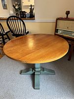 Full view of round dining table showing natural wood top and teal base