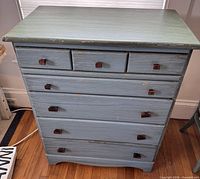 Front view showing all seven drawers and knobs, paint wear