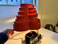 Front view showing ceramic base, figures, and entire tiered red metal shade