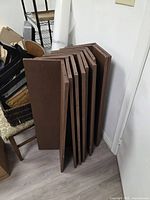 Stack of brown shelf boards leaning against wall