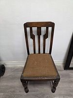 Full frontal view of wooden side chair showing backrest design, seat upholstery, and leg style