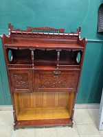 front view showing overall design, missing bottom shelf and carved doors