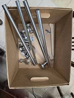 Box containing chrome towel bar rails and assorted hardware
