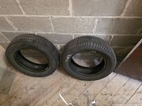 Two of the used tires leaning against cinderblock wall