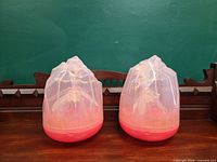 Two Hatchimals Pixies Crystal Flyers in pink crystal pods on wooden surface