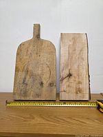 Front view of paddle-style cutting board and live edge slab with tape measure for scale
