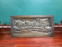 Front view of molded plastic wall plaque showing horse-drawn wagon scene