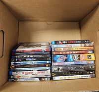 Box containing two stacks of DVD and Blu-ray cases showing visible titles