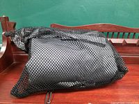 Kayak cover rolled inside black mesh bag on wooden surface