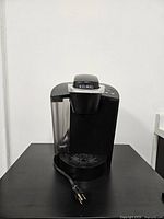 Front view of Keurig brewer showing reservoir, handle, drip tray and power cord