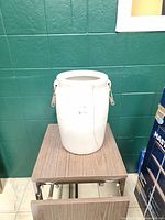 Front view of crock showing overall shape and vertical crack with handle hardware