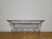 Front view of silver metal wall shelf with hooks