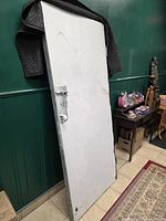 Full view of the salvaged metal door leaning against wall