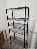 Full view of black wire shelving unit with five shelves and casters