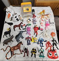 Group view of all action figures, animal figurines, storage tube and accessory on table