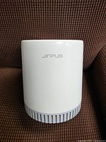 Front view of white Jinpus air purifier showing logo and intake grille