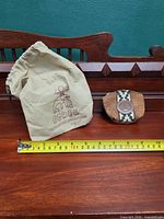 Leather coin pouch with woven strap and drawstring bag beside measuring tape showing width